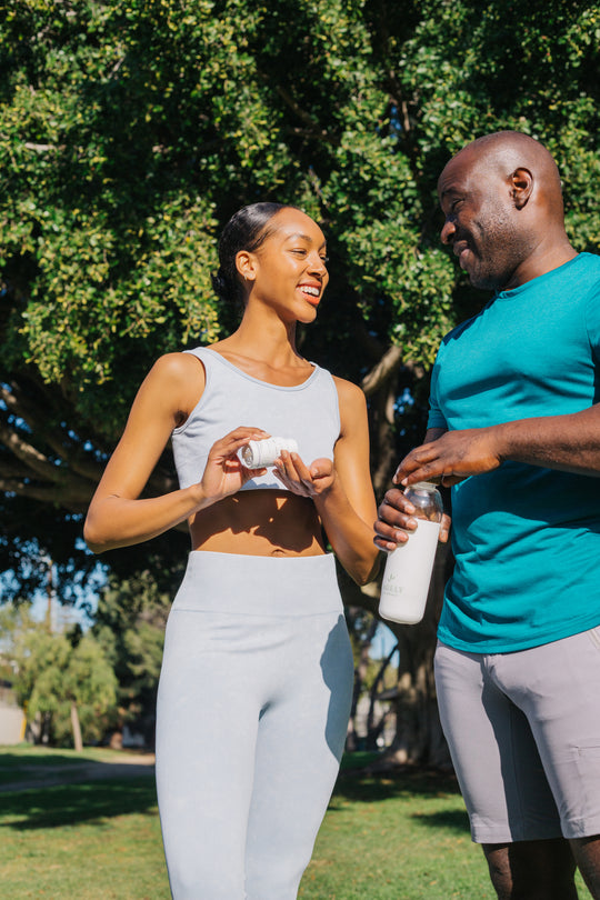Man and woman exercising outdoors while drinking water and taking Sagely Naturals CBD capsules