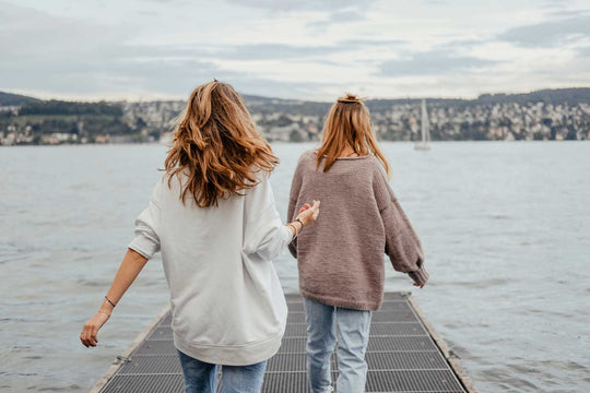 Two women walking on a pontoon toward the water's edge.