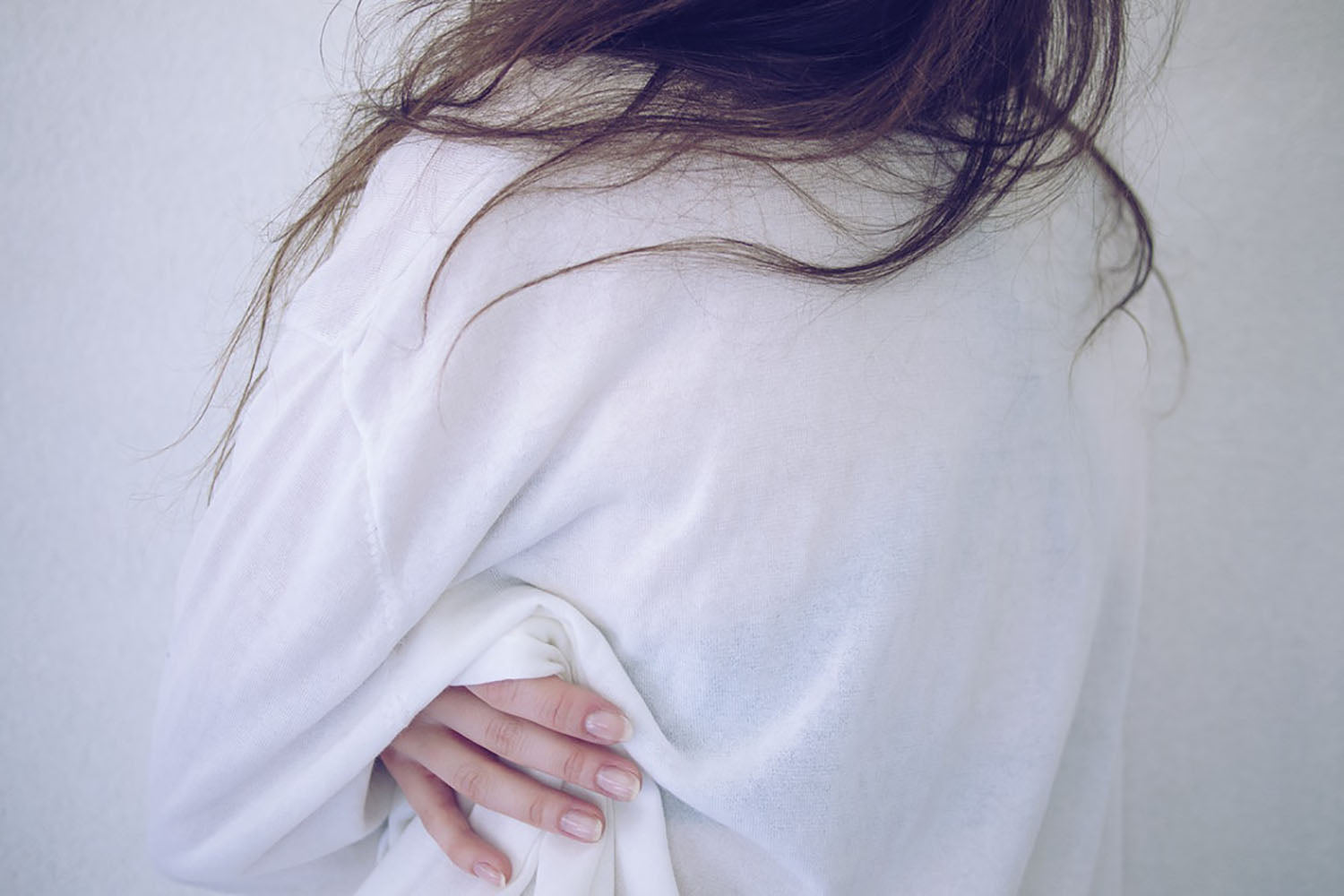 A photo of a woman in a white shirt holding her back and hips