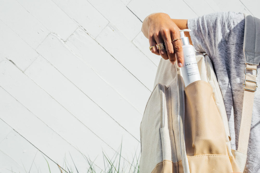 A woman putting Sagely Naturals Calm & Centered CBD Cream into her backpack, standing outside