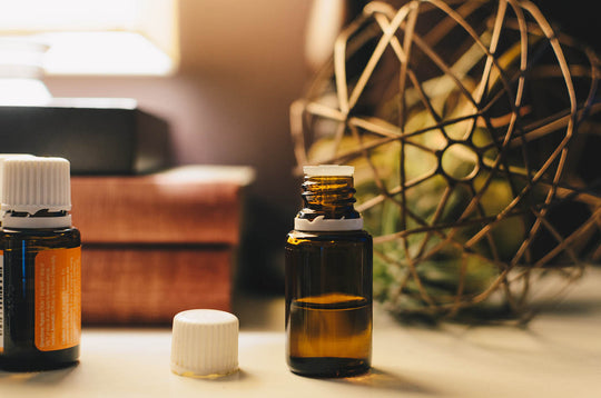 Two essential oil bottles on a table in front of books