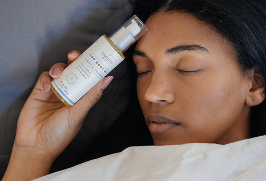 Woman in bed holding her Sagely Naturals Drift & Dream CBD Body Oil