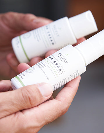A person holding two bottles of Sagely Naturals CBD Spray & Cream in their hands.