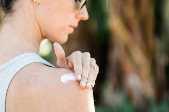 A woman rubbing Sagely Naturals CBD cream into her shoulder.