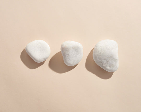 A photo of three white rocks on a beige background