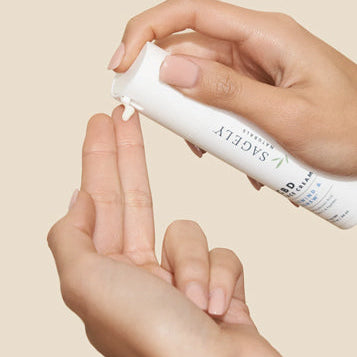 A woman applying Sagely Naturals CBD Rewind & Renew Face Cream to the tips of her fingers.