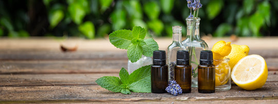 A photo of essential oils next to glass bottles, lemons and mint leaves
