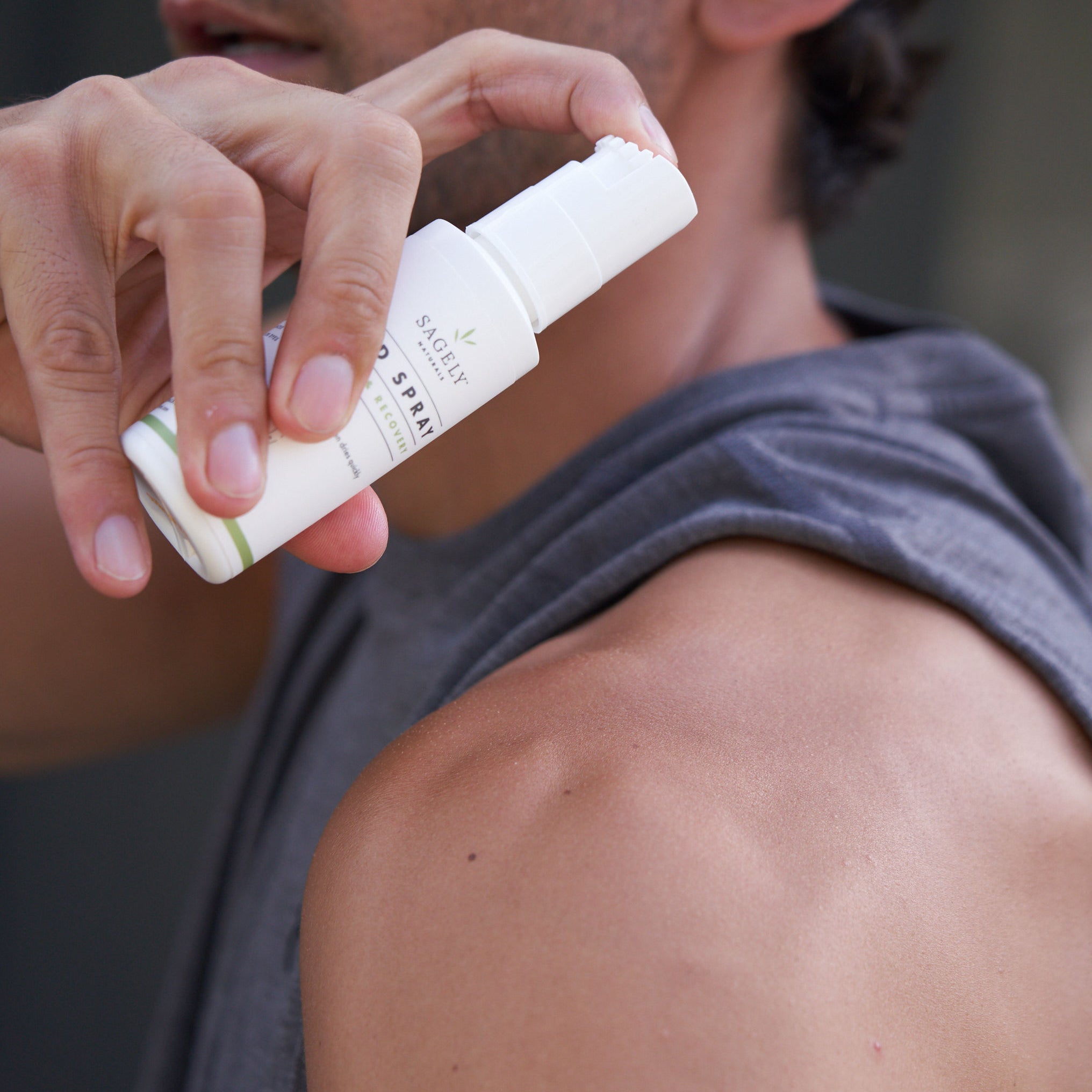 Marathon Runner using Sagely Naturals CBD Spray on his shoulder before working out