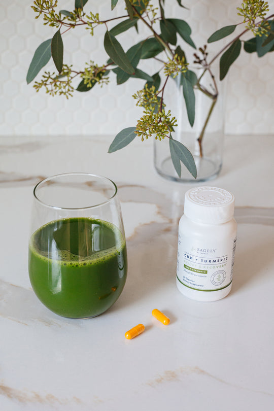 Sagely Naturals Extra Strength Relief & Recovery CBD + Turmeric Capsules on a counter top with a green smoothie