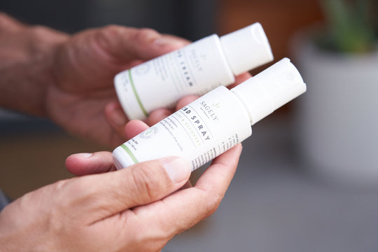 A man holding Sagely Naturals Relief & Recovery CBD Spray and CBD Cream, both travel sized