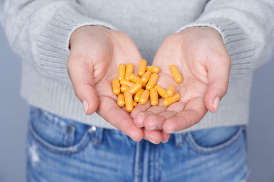 Woman holding Sagely Naturals CBD + Turmeric capsules in her hands.