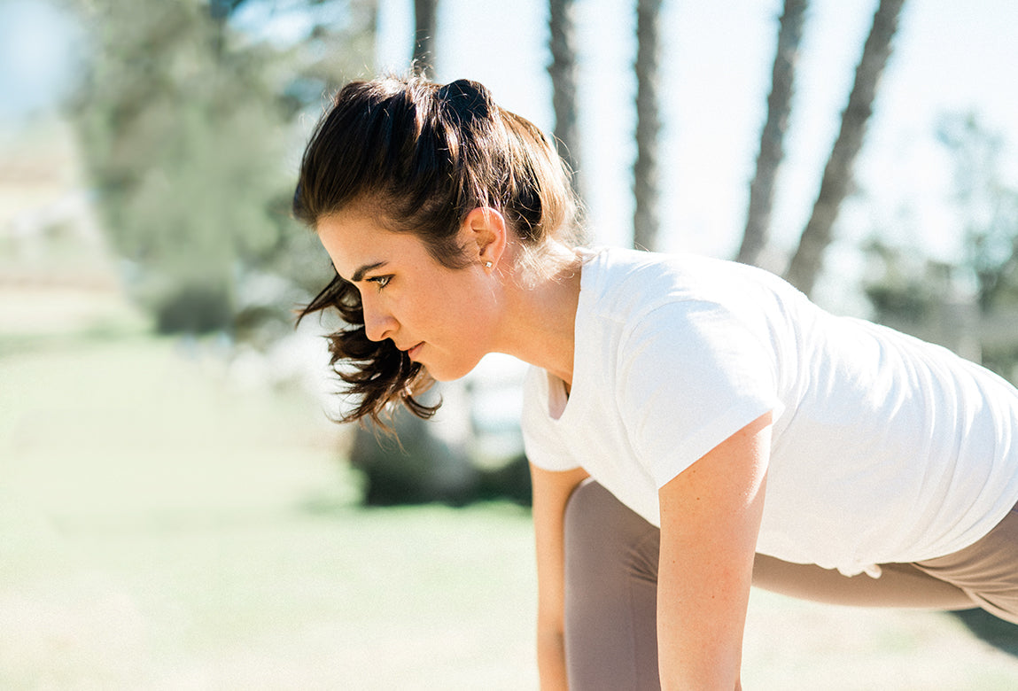 Woman doing a runners stretch with a bottle of Relief & Recovery CBD Cream