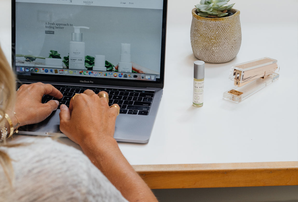Woman sitting at a white desk typing on her computer.