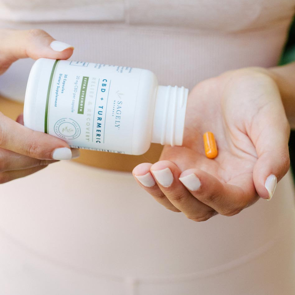 A woman pouring Sagely Naturals Relief & Recovery Extra Strength CBD Capsules into her hand