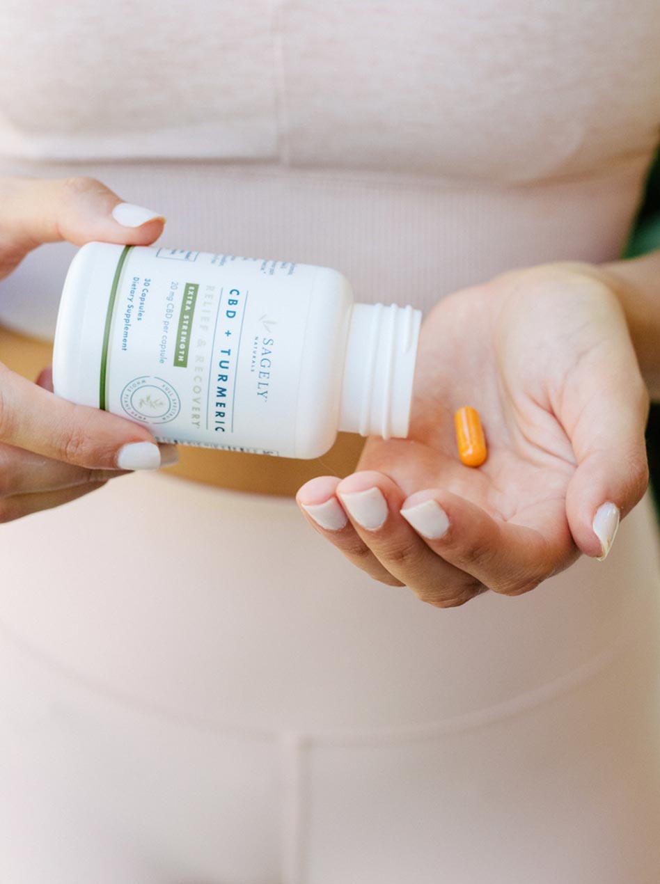 A woman pouring Sagely Naturals Relief & Recovery Extra Strength CBD Capsules into her hand