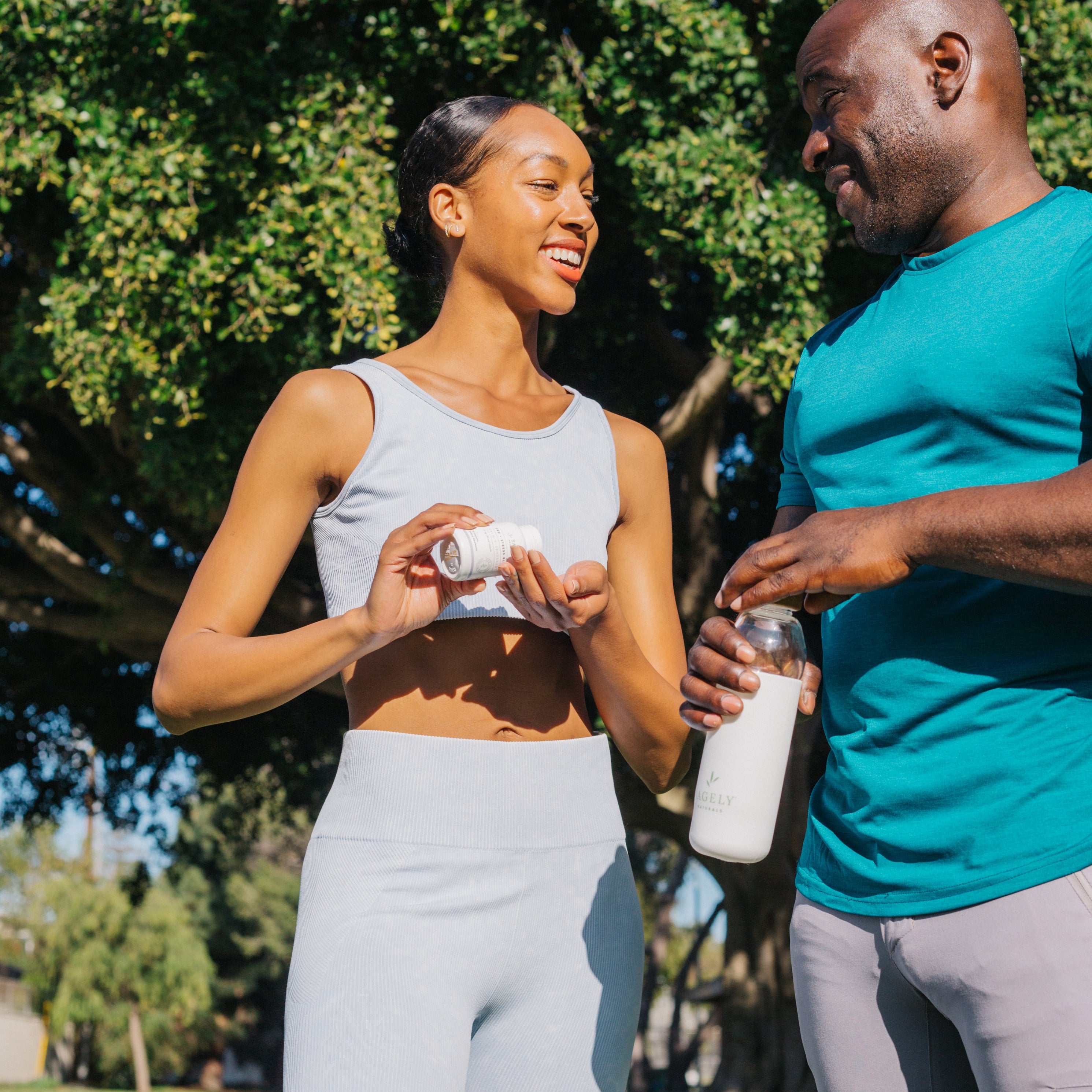 Man and woman exercising outdoors while drinking water and taking Sagely Naturals CBD capsules