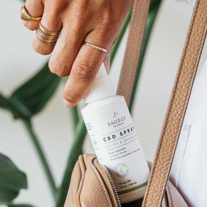 A Woman taking out of her purse her Sagely Naturals Relief & Recovery CBD Spray